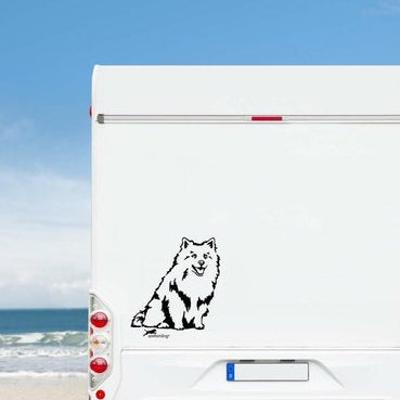 Schwarzer Deutscher Spitz Aufkleber auf einem weißen Wohnmobil am Meer unter blauem Himmel – wetterfestes Wohnmobil-Aufkleber-Motiv von amberdog