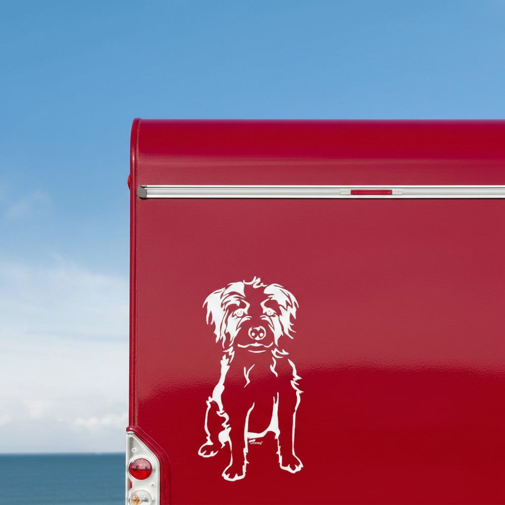 Weißer Kromfohrländer Ganzkörper Aufkleber am Heckbereich eines roten Wohnmobils vor Meer und Himmel, wetterfestes Autoaufkleber-Motiv von amberdog