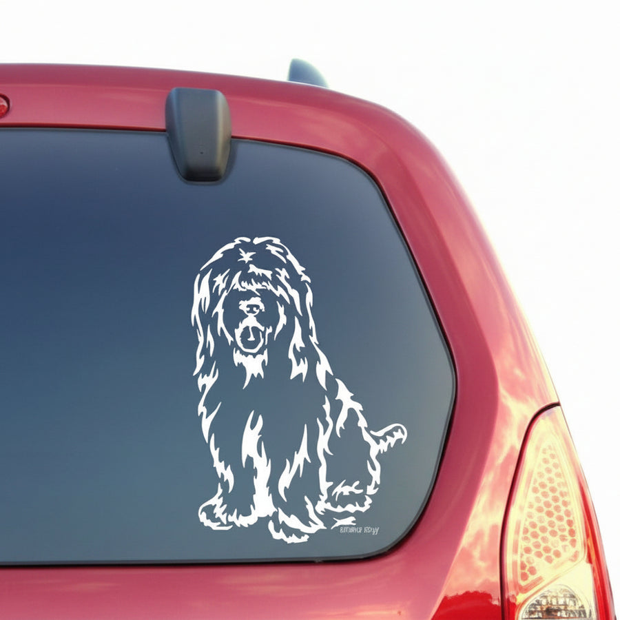 Weißer sitzender Briard Aufkleber an der Heckscheibe eines roten Autos – wetterfestes Wandtattoo- und Autoaufkleber-Motiv von amberdog