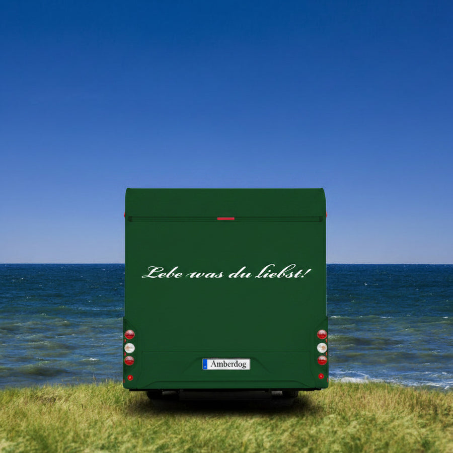 Wohnmobil-Aufkleber „Lebe was du liebst“ weiß am grauen Wohnmobil am Meer | amberdog®