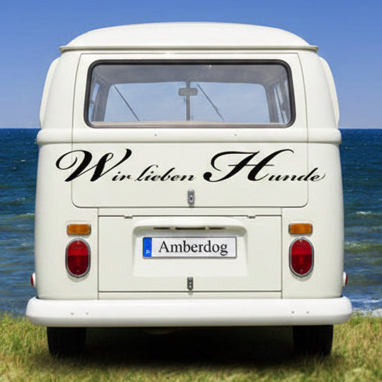 VW-Bus Heck mit schwarzem Aufkleber „Wir lieben Hunde“ am Meer | amberdog®