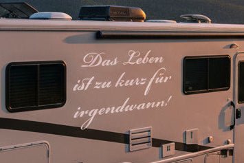 Wohnmobil mit Aufkleber „Das Leben ist zu kurz für irgendwann!“ bei Sonnenuntergang | amberdog®